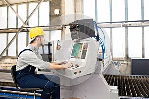 Factory operator working on control panel of manufacturing machi