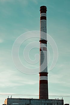 Factory pipe on the background of the blue morning sky. Smokestack made of red brick