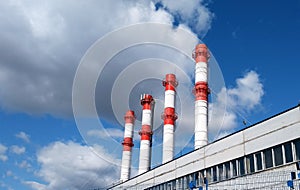 Factory pipes against the blue sky with clouds