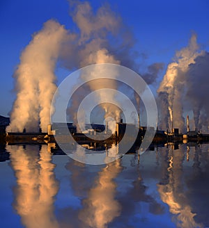 Factory Pollution in the Sky Smoke Rising Pollutants in the Air Reflected in Water Lake or Pond photo