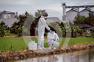 Factory scientists or biologists wear protective clothing while inspecting water quality and pH tests near farmland, Natural water