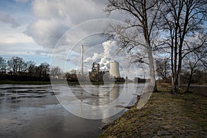 The factory smokes into the air on the shore of a beautiful river