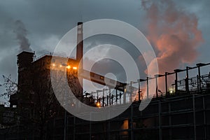 Factory at the sunset, lights and smoke