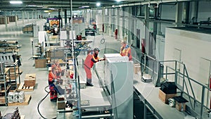 Factory technicians are manually assembling refrigerators