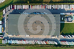 Factory warehouse with parked semi trucks, aerial view