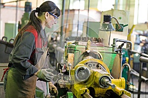 Factory woman turner working on workshop lathe machine photo