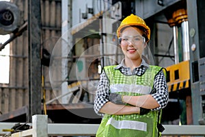 Factory woman worker or technician with safety uniform and stand with confident action in workplace in front of machine. Concept