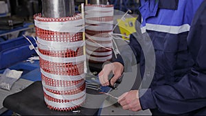 Factory worker assembling electric equipment - transformer - on assembly Line. High voltage components Manufacturing.