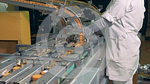 Factory worker is directing the process of biscuits manufacturing by the industrial machine