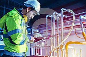 Factory worker engineer working in factory using tablet computer to check maintenance boiler water pipe in factory