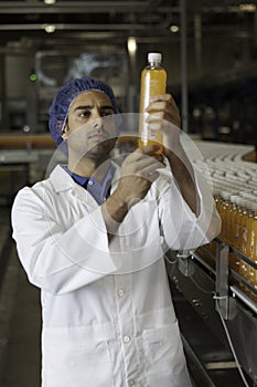 Factory worker examining orange juice bottle