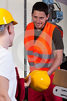 Factory worker giving his collaborator hardhat photo