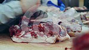 Factory worker is grinding a knife and cutting meat