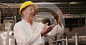 Factory worker inspecting a glass bottle at bottling plant