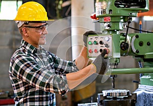 Factory worker man stand and press button of the machine to work in workplace also look happy by smiling. Concept of good