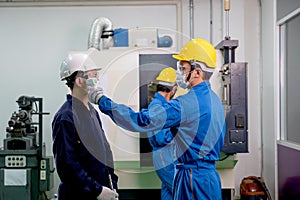 Factory worker man use infrared thermometer for measure and screening temperature of other co-workers in industrial workplace.