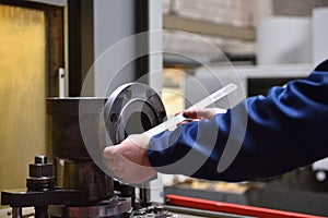 A factory worker measures with a ruler the diameter of the valve`s circumference before machining with a CNC machine