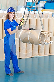 Factory worker moving transformer coil with overhead crane