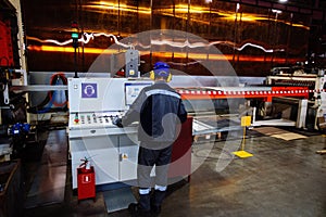 Factory worker operating CNC machine in metalworking workshop