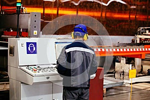 Factory worker operating CNC machine in metalworking workshop