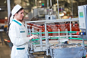 Factory worker operating conveyor with beer beverage bottles mov