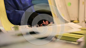 Factory worker for production of airplanes tighten nut with a wrench, view from inside of fuselage.