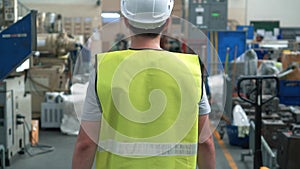 Factory worker with safety hard hat walking through industrial facilities