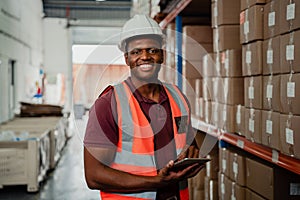 Factory worker smiling holding digital tablet organising parcels in warehouse