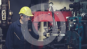 Factory worker talking on portable radio while inspecting machinery parts