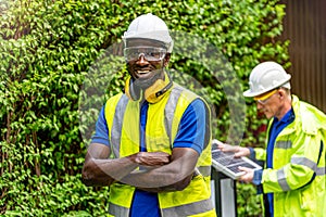 Factory worker technician engineer man standing confidence with green working suite dress and safety helmet in front worker