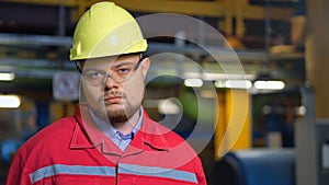 Factory worker in uniform posing on industrial plant