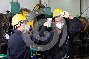 Factory worker using digital thermometer for checking fever, protect from coronavirus covid-19