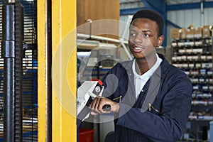 Factory Worker Using Powered Fork Lift To Load Goods