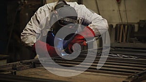 Factory worker is welding metal in a workshop of plant