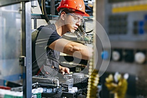 Factory worker working in industrial building indoor. Man fixing machines, checking work process, fixing techniciall problems