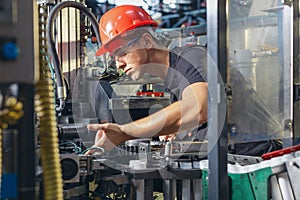 Factory worker working in industrial building indoor. Man fixing machines, checking work process, fixing techniciall problems