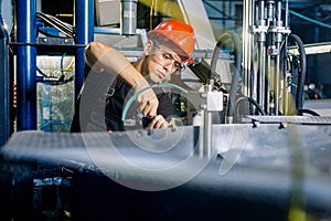 Factory worker working in industrial building indoor. Man fixing machines, checking work process, fixing techniciall problems