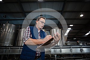 Factory worker writing on clipboard in factory