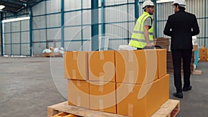 Factory workers deliver boxes package on a pushing trolley in the warehouse .