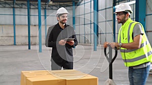 Factory workers deliver boxes package on a pushing trolley in the warehouse .