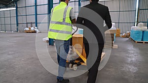 Factory workers deliver boxes package on a pushing trolley in the warehouse .