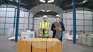 Factory workers deliver boxes package on a pushing trolley in the warehouse .