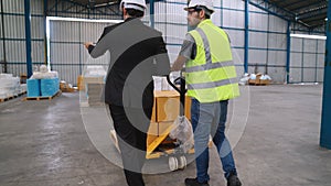 Factory workers deliver boxes package on a pushing trolley in the warehouse .