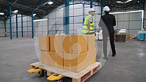 Factory workers deliver boxes package on a pushing trolley in the warehouse .