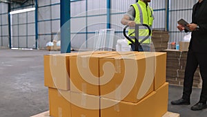 Factory workers deliver boxes package on a pushing trolley in the warehouse .