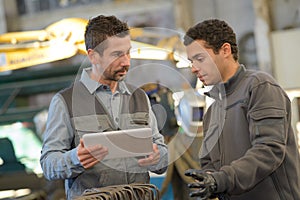 Factory workers discussing with digital tablet in warehouse