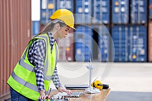 Factory workers or engineers holding light bulb and using tablet computer with windmill model on solar panel,  work in containers