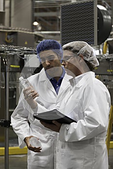 Factory workers inspecting bottled water at bottling plant