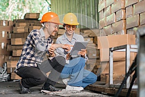 factory workers men and women wear safety helmets using a tablet