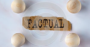 FACTUAL - word on a brown torn piece of paper on a light background with balls photo